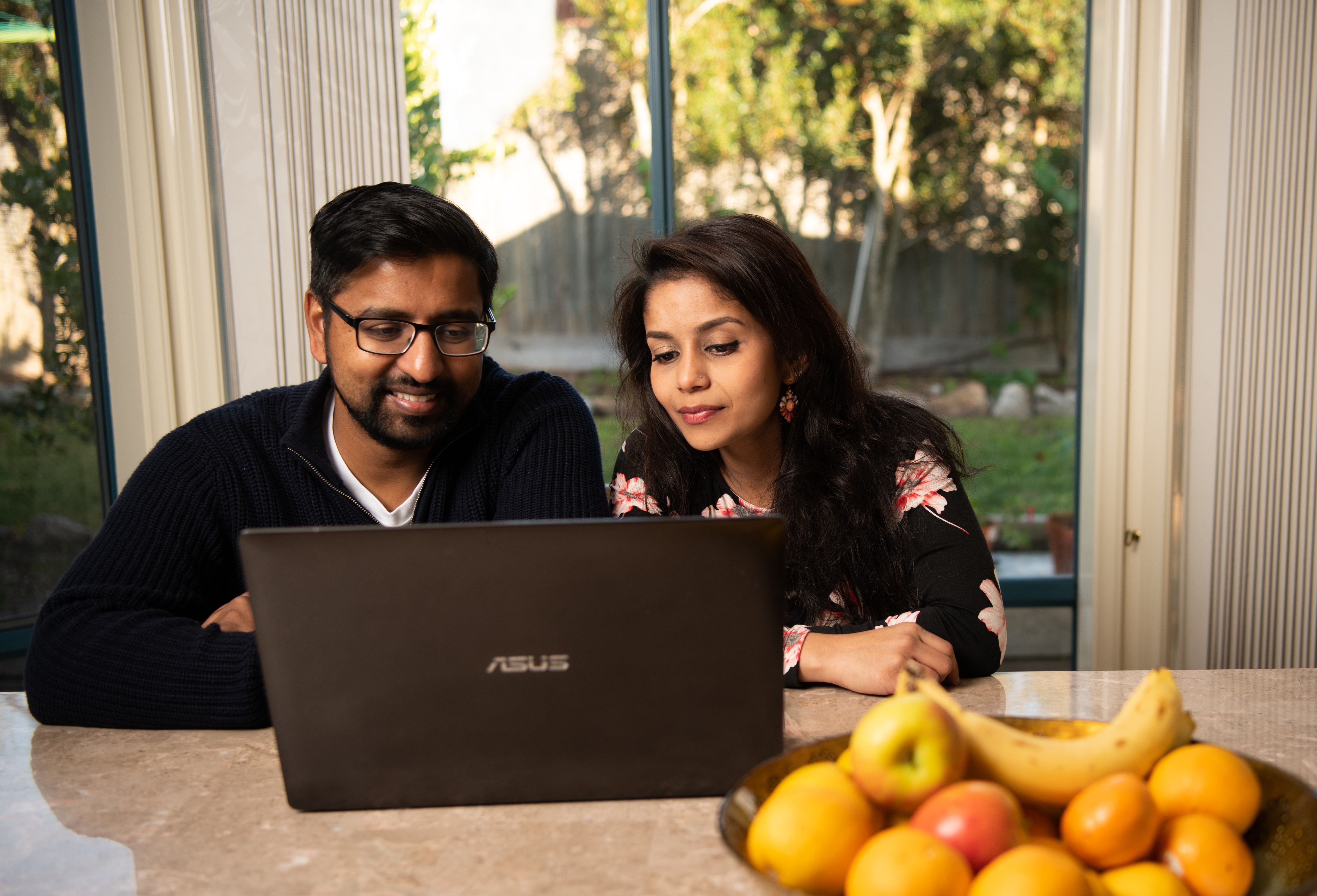 A couple sitting together inside while looking at a laptop