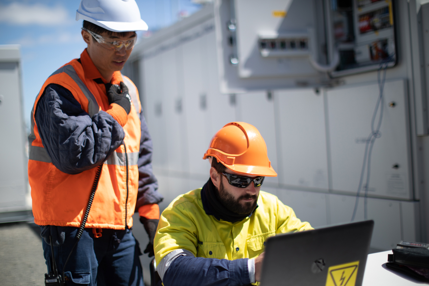 Two workers outside looking at a laptop