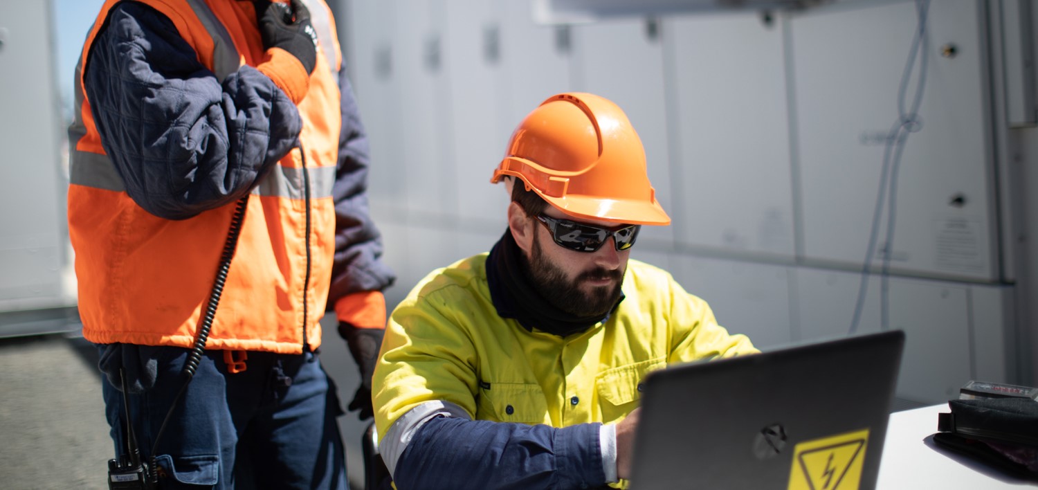 Two workers outside looking at a laptop