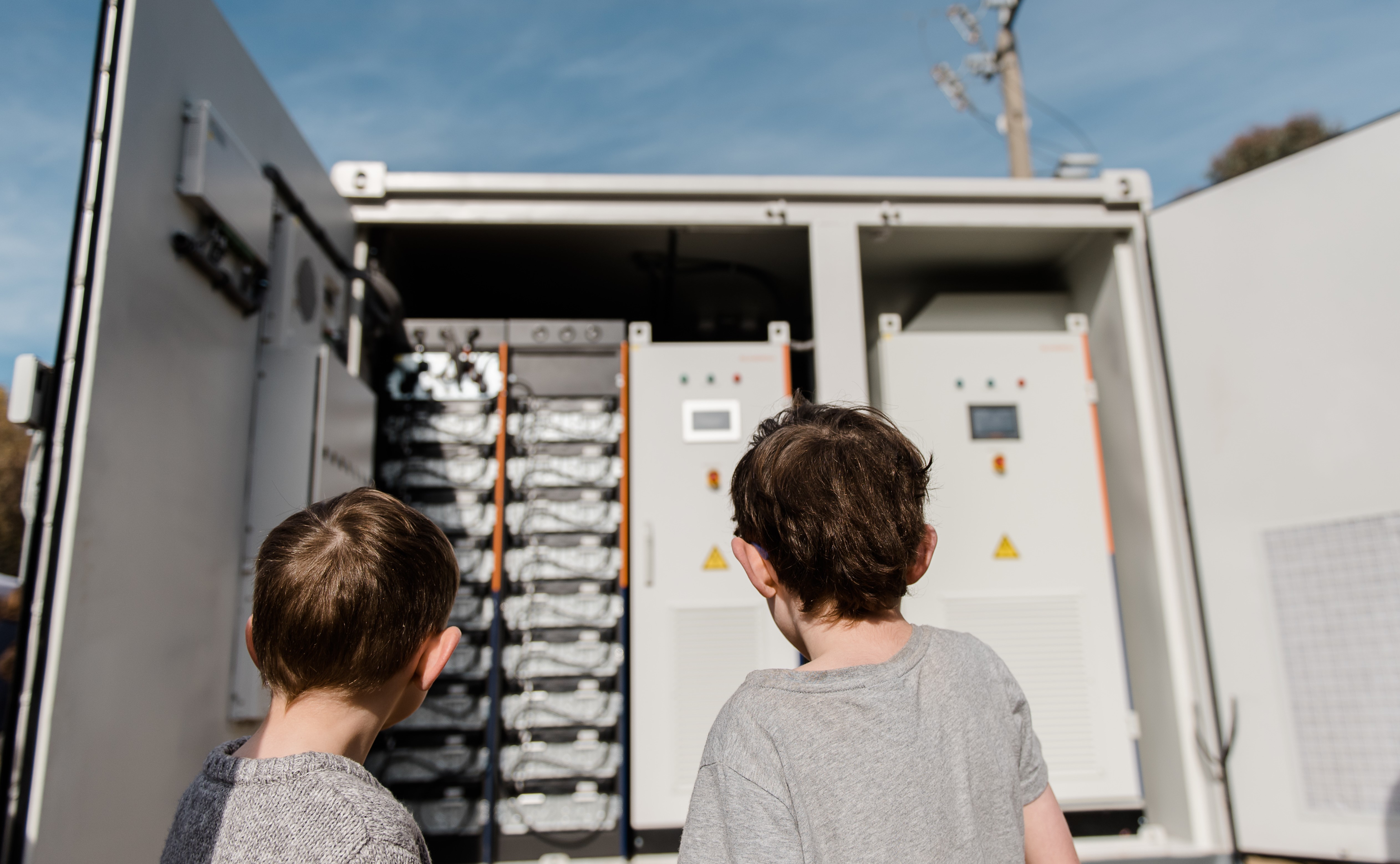 Two young children outside looking at a large battery